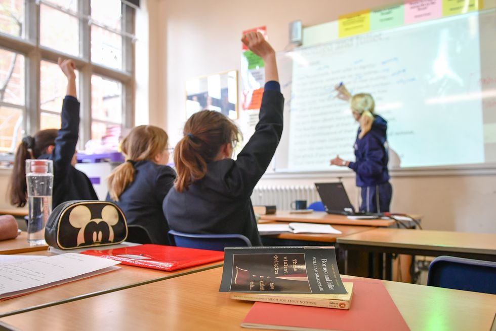 (Stock photo) A pupil raises their hand in a classroom