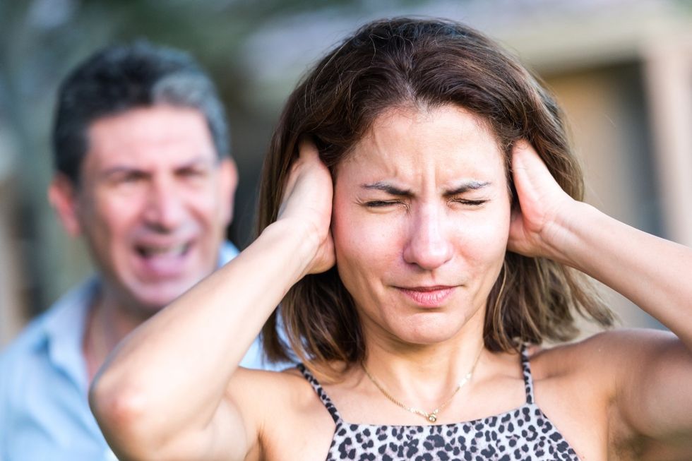 (Stock) Woman covers her ears as man yells at her