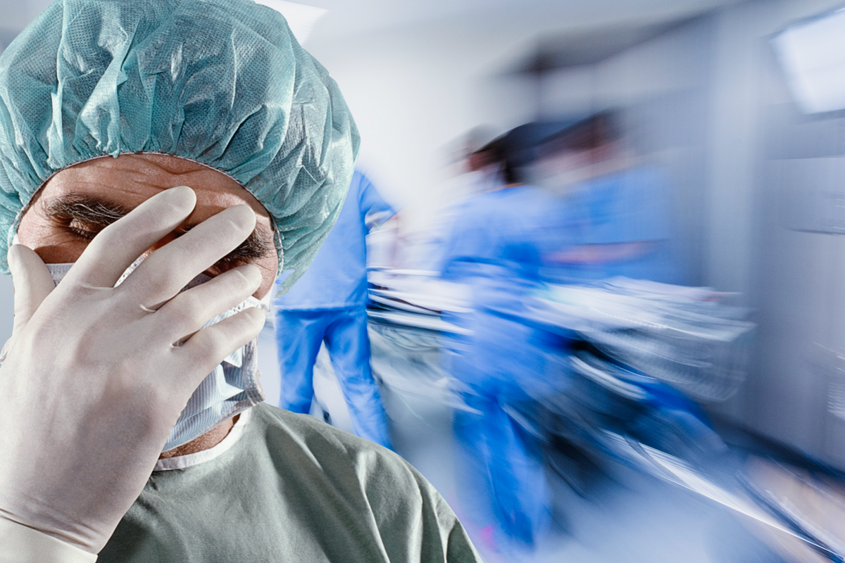 Surgeon with his head in his hands in a busy hospital corridor 