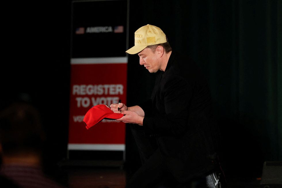 Tesla CEO and X owner Elon Musk, who supports Republican presidential nominee former U.S. President Donald Trump, signs a cap during an America PAC Town Hall in Folsom, Pennsylvania, U.S., October 17, 2024