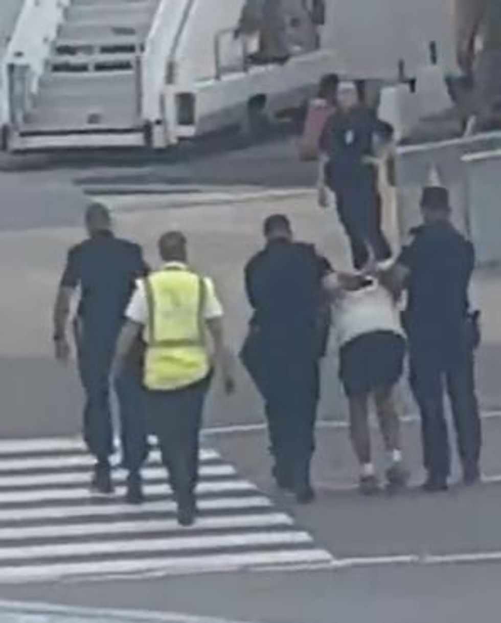 The British tourist, who was wearing a white t-shirt and shorts, was later clipped being escorted off the plane and dragged across the airport\u2019s tarmac