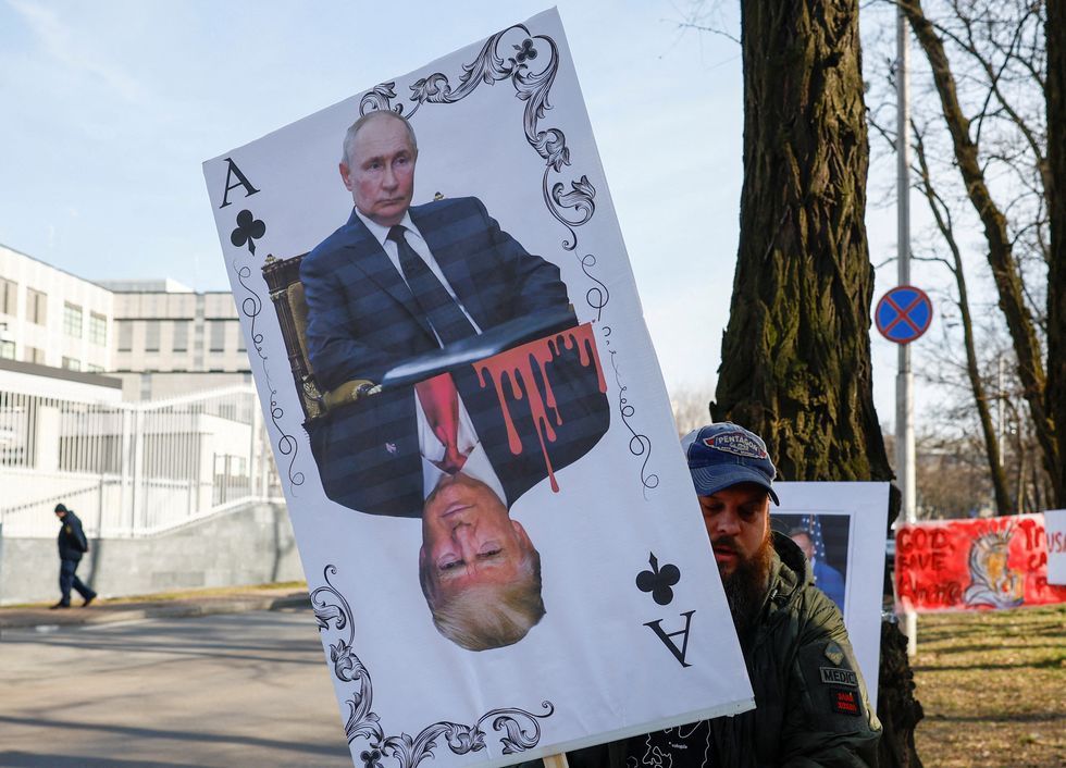 u200b A demonstrator holds a banner depicting a playing card with portraits of Russian President Vladimir Putin