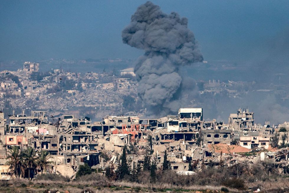 \u200b smoke plume rising from explosions above destroyed buildings in the northern Gaza Strip