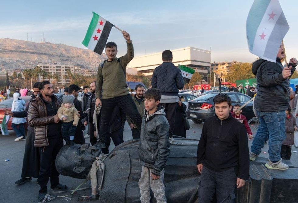 \u200b Syrians bring the demolished statue of Hafez al-Assad to Umayyad Square in the capital Damascu