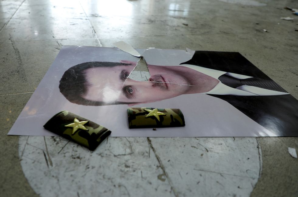 \u200bA damaged picture of Syria's Bashar al-Assad lies on the floor inside Qamishli international airport