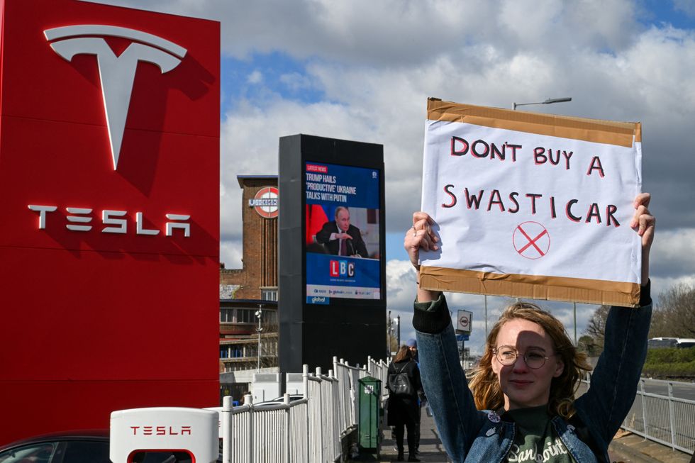 u200bA demonstrator holds an anti-Tesla poster during a protes