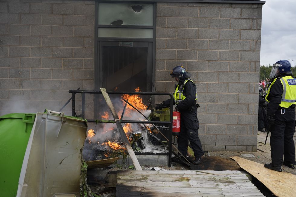 u200bA fire is extinguished by police officers as trouble flares during an anti-immigration protest outside the Holiday Inn Express