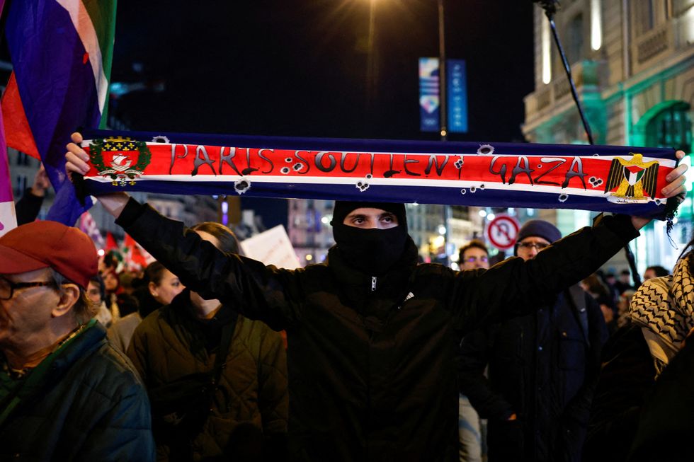 \u200bA man holding up a sign saying 'Paris soutien Gaza' (Paris supports Gaza)