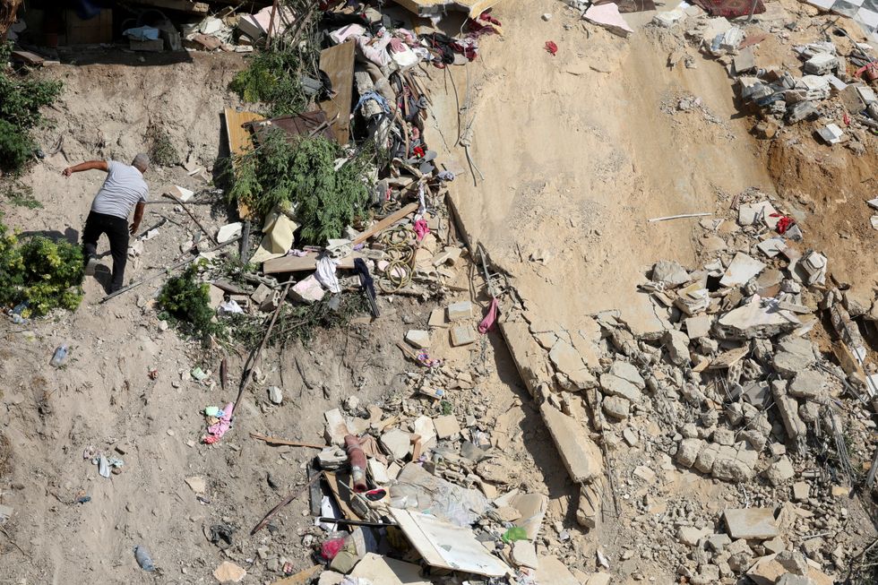 \u200bA man walks amidst the rubble at the site of Sunday's Israeli attack on the city of Ain Deleb