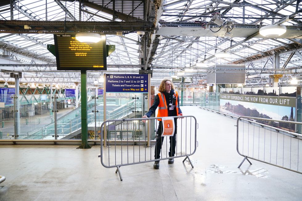 u200bA member of staff places barriers and closes the entrance to Waverley Station in Edinburgh