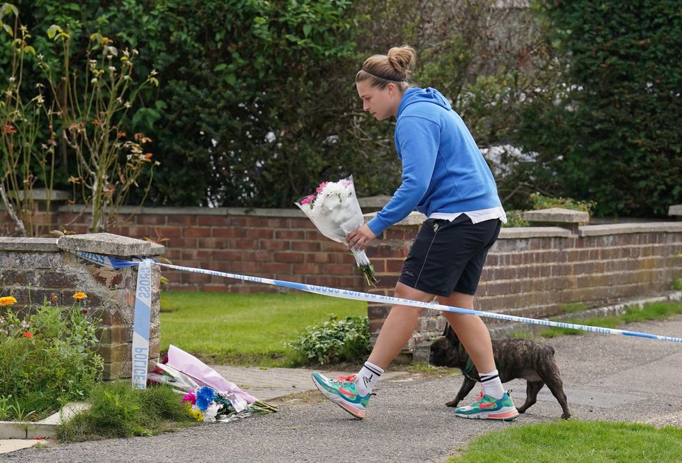 u200bA person leaves flowers outside a property on Hammond Road in Woking, Surrey,