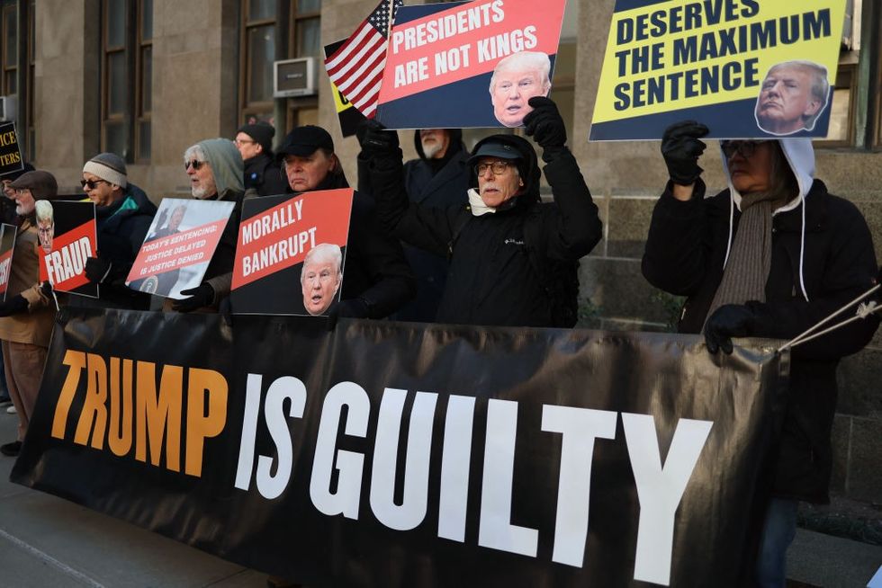 u200bAnti-Trump supporters hold signs outside the Manhattan Criminal Court in New York