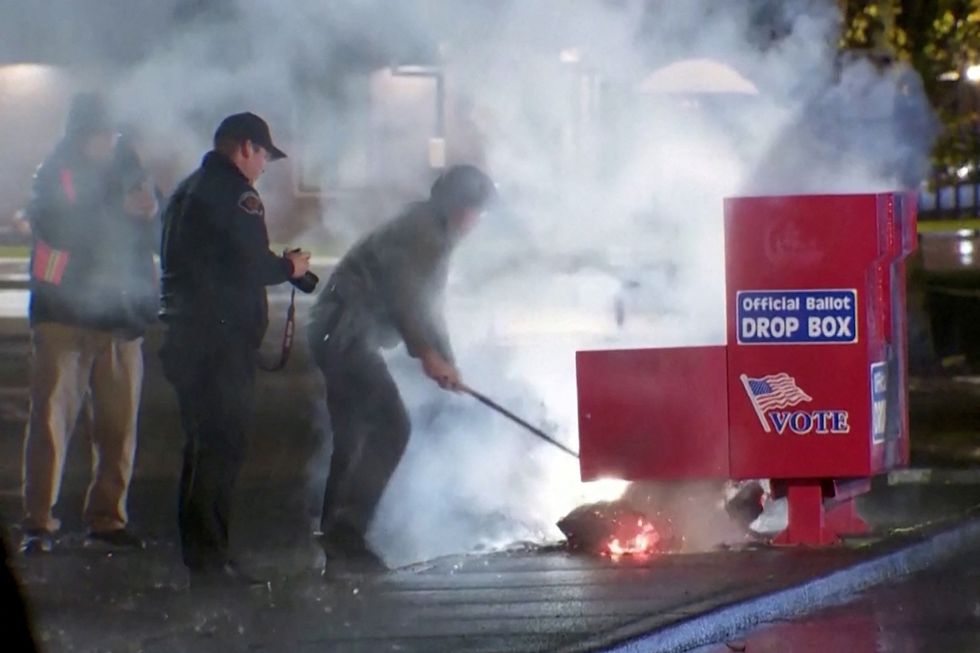 u200bFirst responders pull out the burning contents of a ballot box