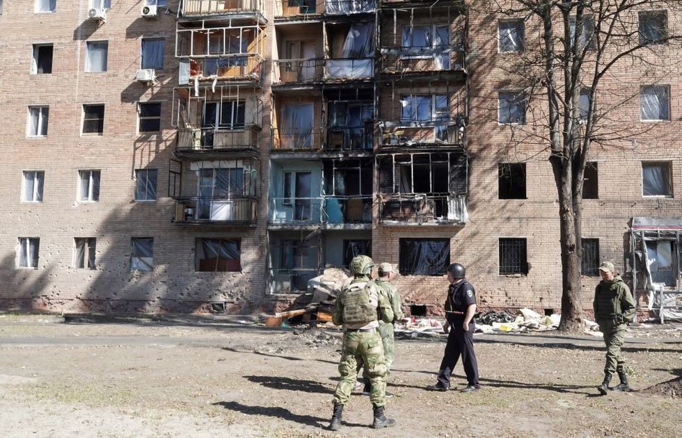 u200bLocal volunteers walk past a building damaged by Ukrainian strikes in Kursk on August 16, 2024,