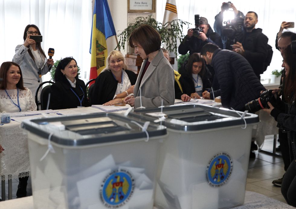 u200bMoldova's incumbent President and presidential candidate Maia Sandu stands in front of members of a local electoral commission at a polling station