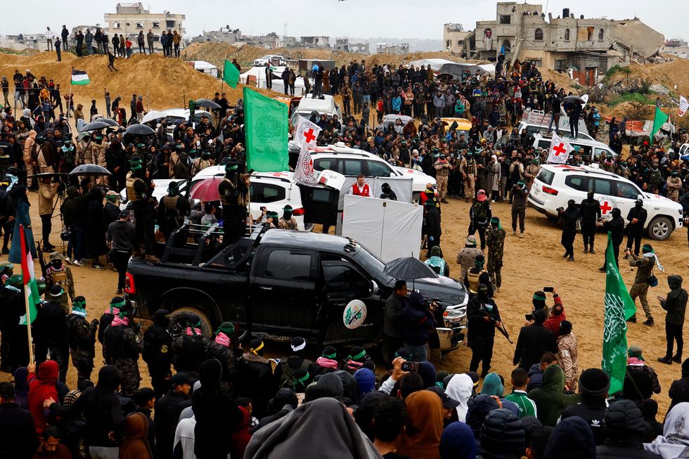 u200bPalestinian militants and members of the Red Cross gather near vehicles on the day Hamas hands over deceased hostages