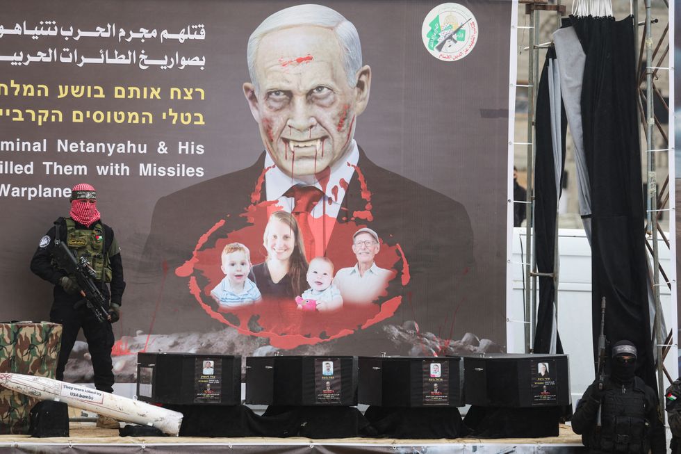 u200bPalestinian militants stand near coffins during the handover of deceased hostages Oded Lifschitz, Shiri Bibas and her two children Kfir and Ariel Bibas