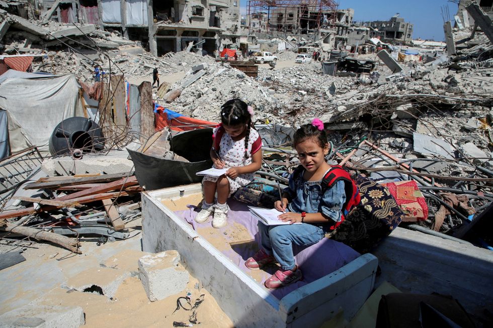 u200bPalestinian students sit on the rubble after attending a class in a tent set up on the ruins of the house of teacher Israa Abu Mustafa