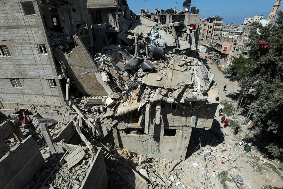 u200bPalestinians walk past a house hit in an Israeli strike, amid the Israel-Hamas conflict, in Bureij refugee camp, in the central Gaza Strip