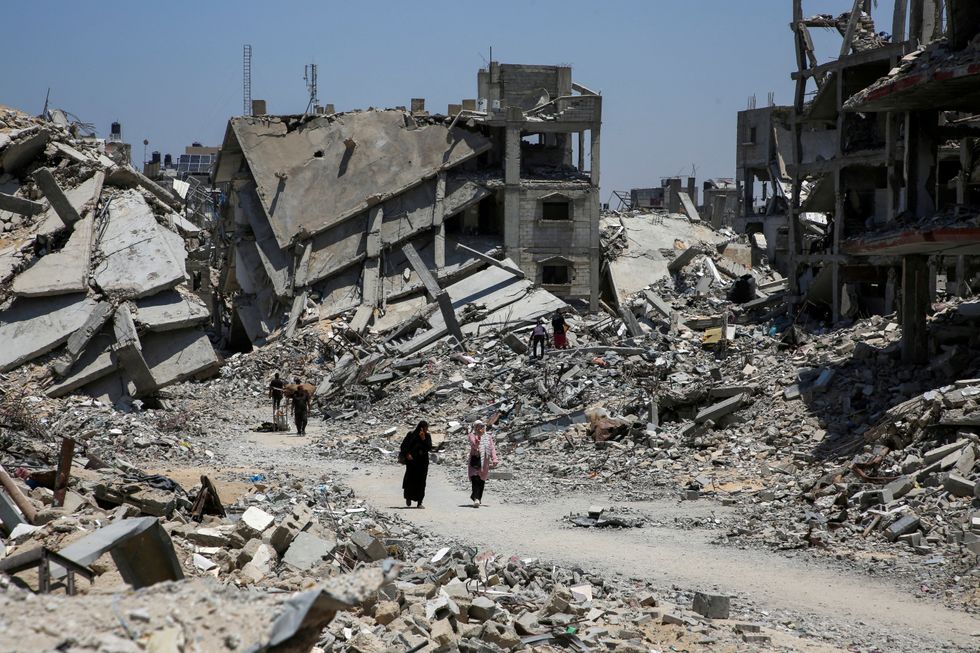 \u200bPalestinians walk past the rubble of houses destroyed during the Israeli military offensive