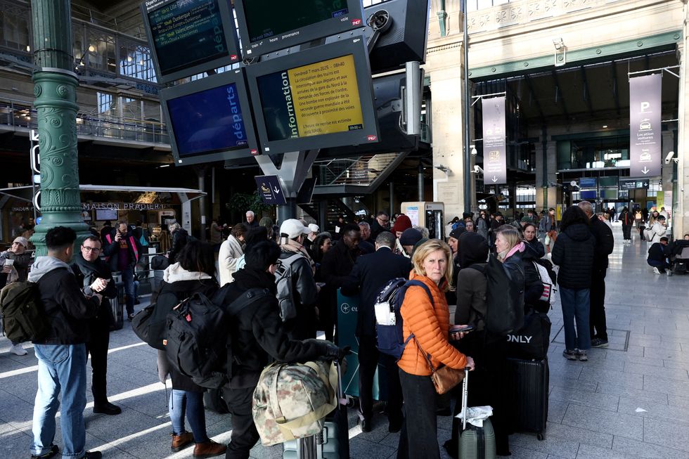 u200bPassengers stand next to information screens at the departure hall