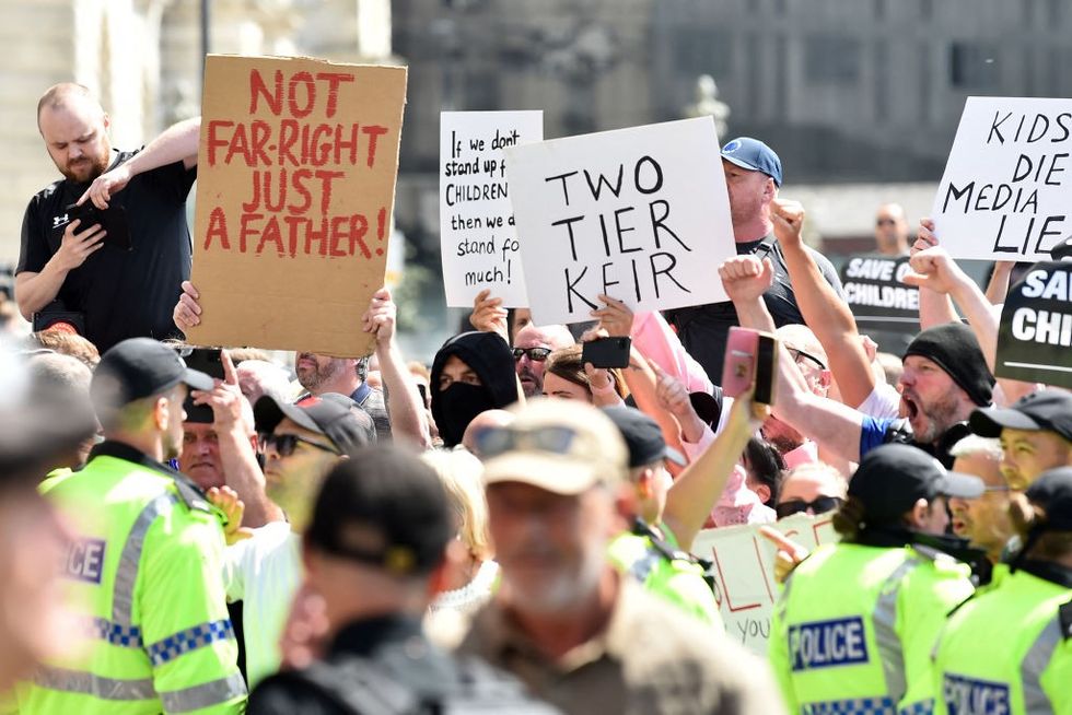 u200bPolice officers stand guard as protesters hold placards outside the Liver Building in Liverpool