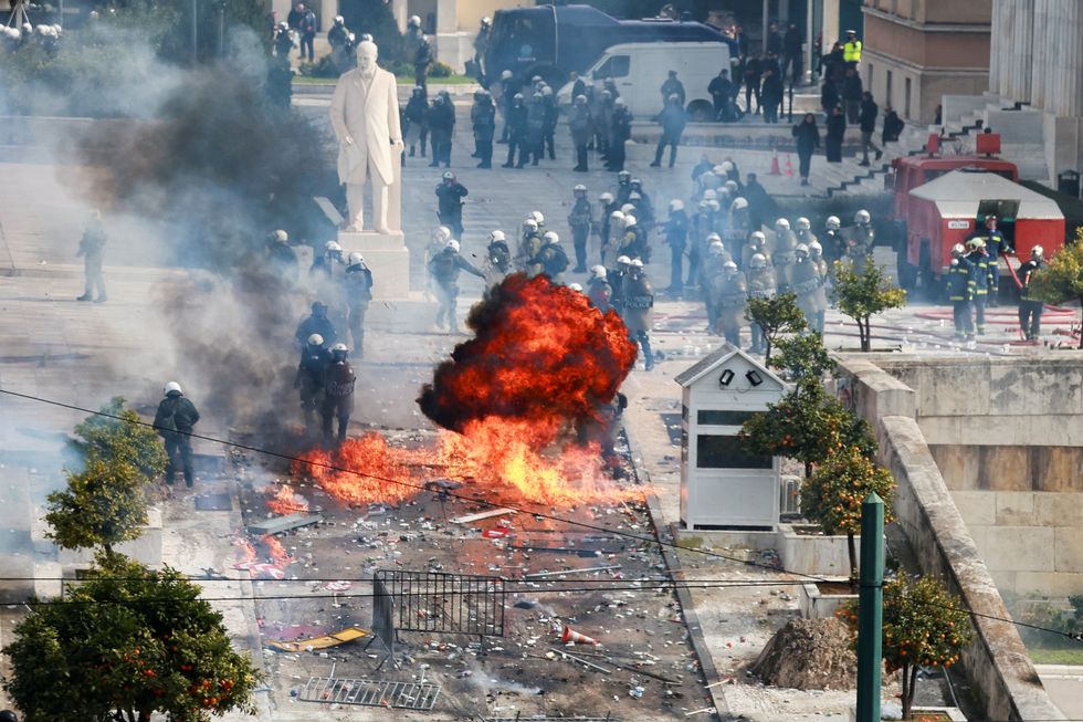 \u200bPolice stand next to fire during clashes near the Greek parliament