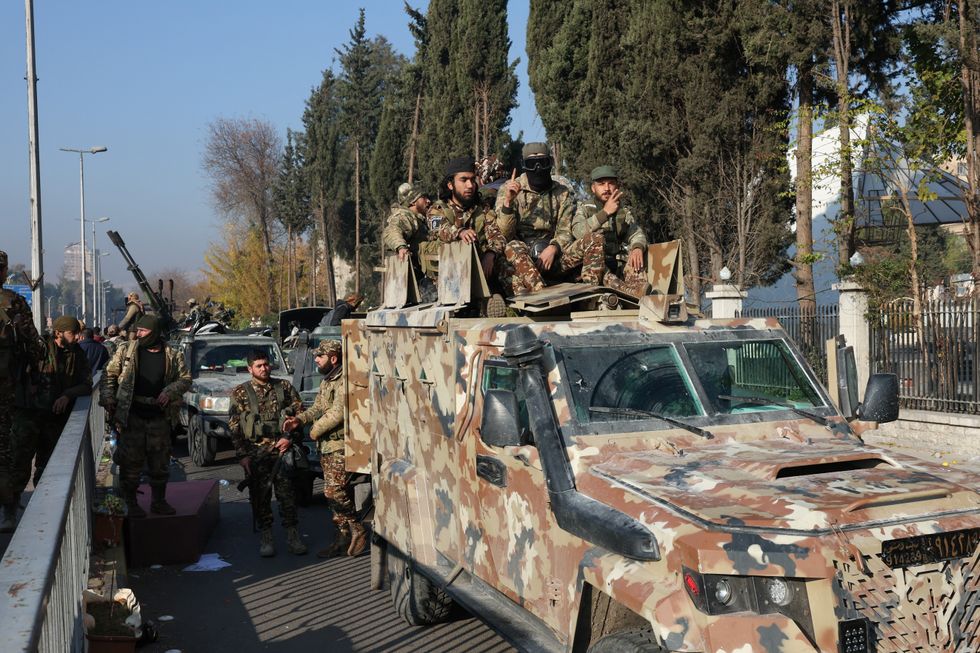 u200bRebel fighters sit on a vehicle, after rebels seized the capital and ousted President Bashar al-Assad