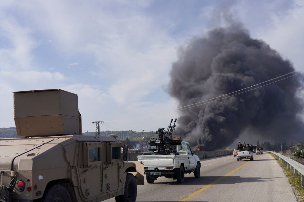 \u200bSmoke rises while members of the Syrian forces ride on a vehicle as they battle against a nascent insurgenc