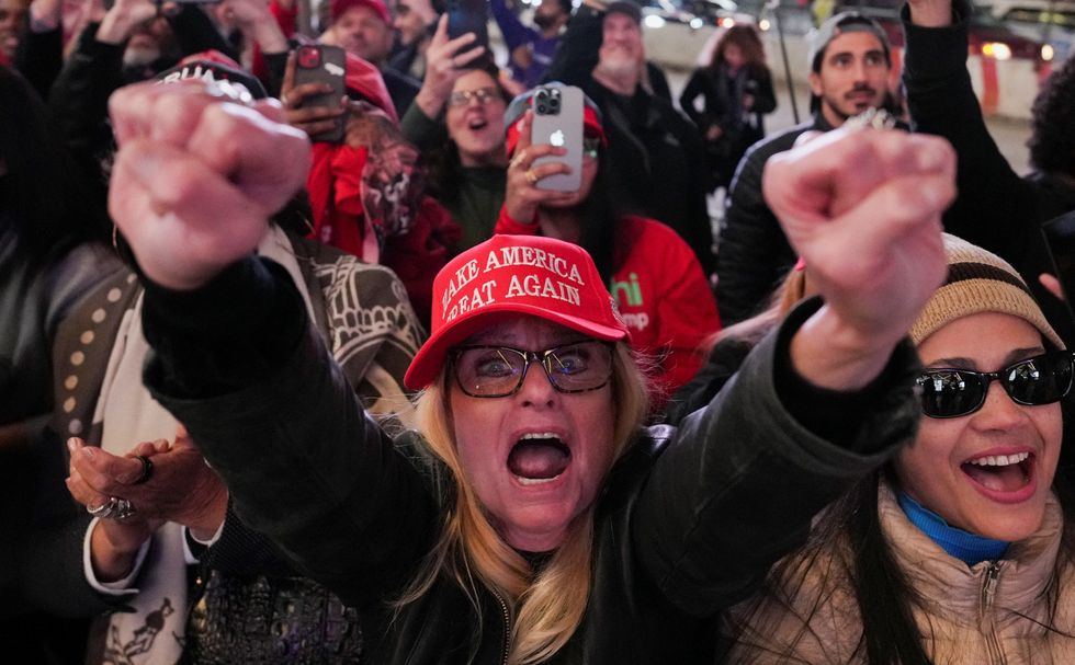 \u200bSupporters cheer as they watch a live transmission on a screen during a rally for Trump