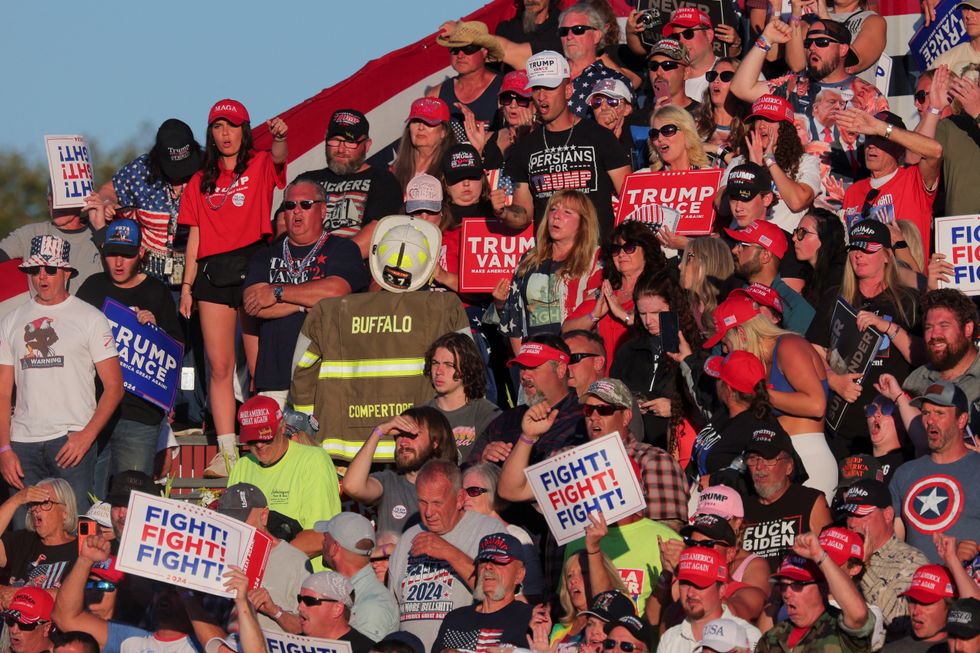 \u200bSupporters hold signs and a firefighter uniform reading Compertore during a campaign rally held by Republican presidential nominee