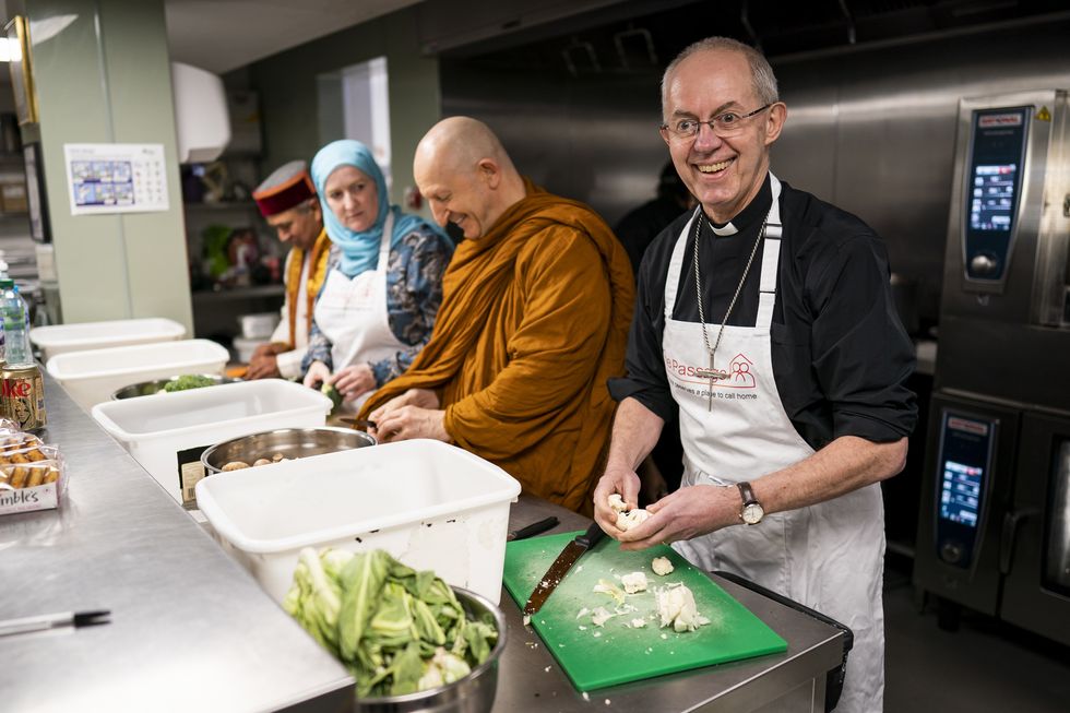 \u200bThe Archbishop of Canterbury Justin Welby (right) prepares food as he joins other faith leaders in taking part in the Big Help Out, at the Passage in London