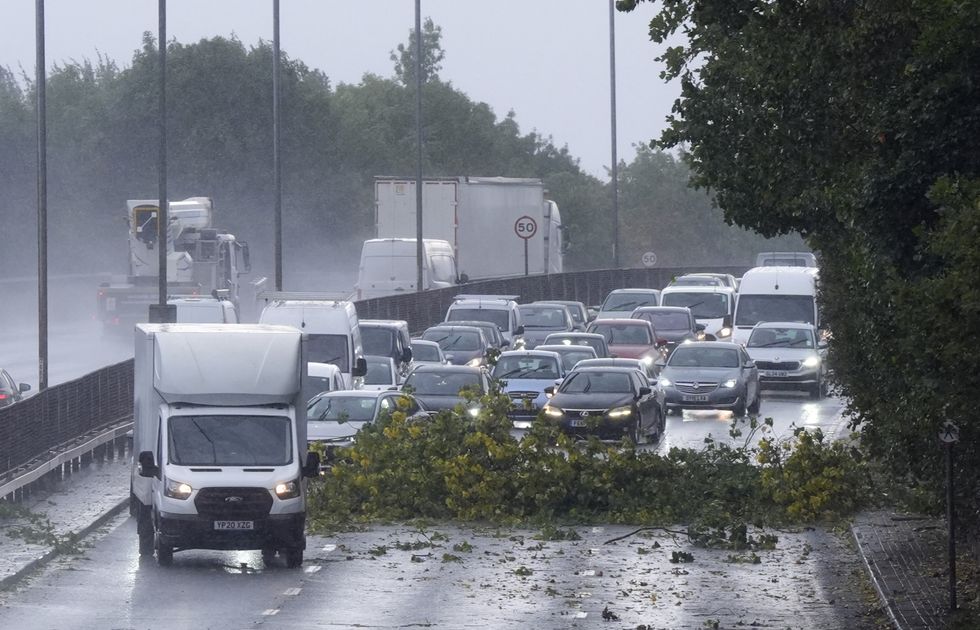 u200bVehicles negotiate debris from a tree on the North Circular in London