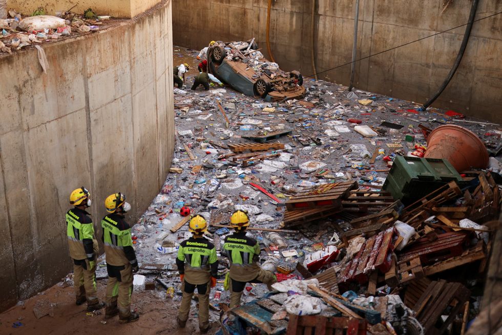 u200bWorkers stare at mountain of rubbish and mud in Valencia