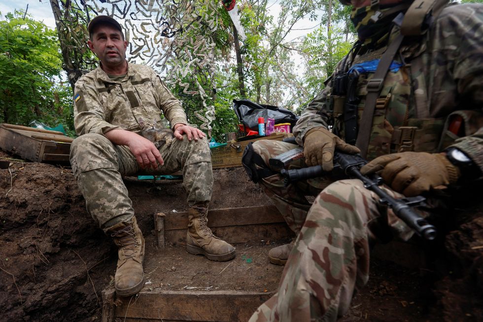 Ukrainian troops sit in a trench near the recaptured village of Novodarivka