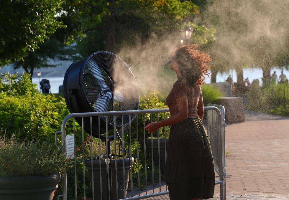 Woman dealing with heatwave by having a fan blow water on her 