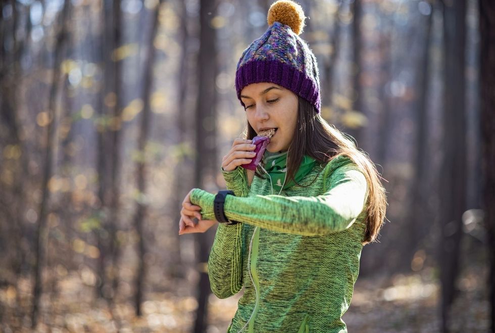 Woman eating protein bar while running