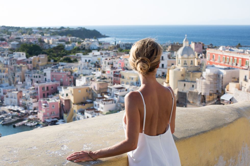 Woman enjoying the view of the idyllic port of Corricella, Procida Island, Italy - stock photo