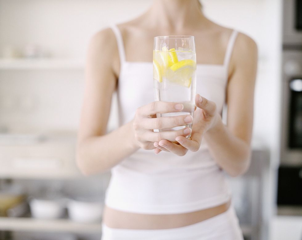 Woman holding a glass of water with lemon