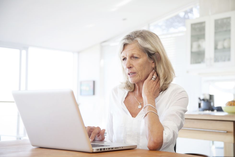 Woman looks worried while looking at laptop