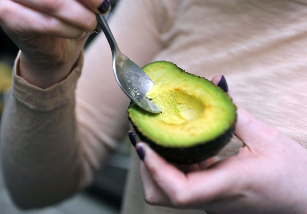 Woman scooping avocado with a spoon